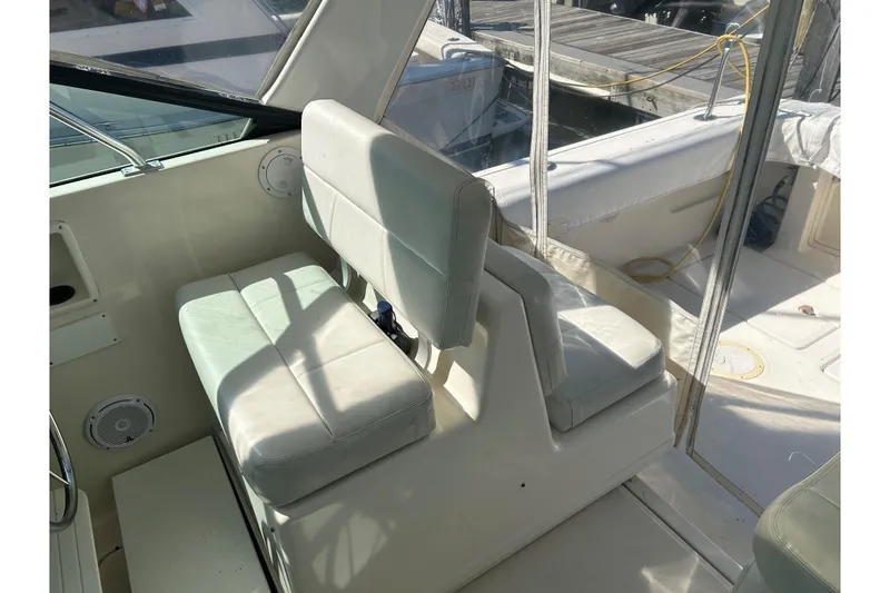 Slide: The Image of 1993 Tiara Yachts 3100 Open interior with white cushioned seating and dock view. - 7