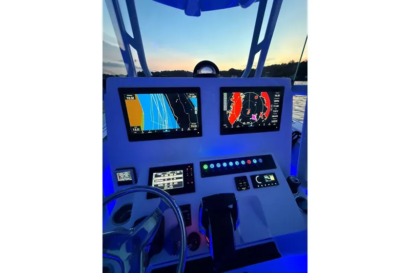 Slide: The Image of 2025 Cape Horn 34 XS boat dashboard with illuminated navigation screens at sunset. - 2