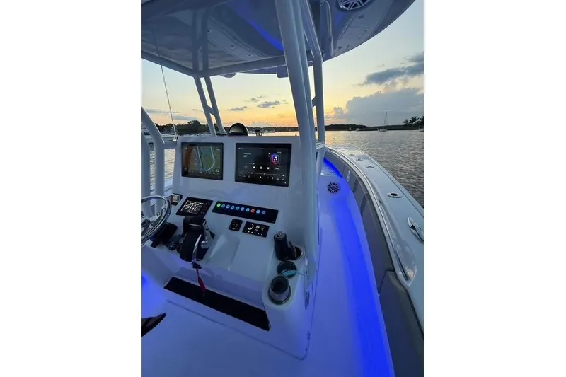 Slide: The Image of 2025 Cape Horn 34 XS boat console with illuminated controls at sunset on the water. - 6