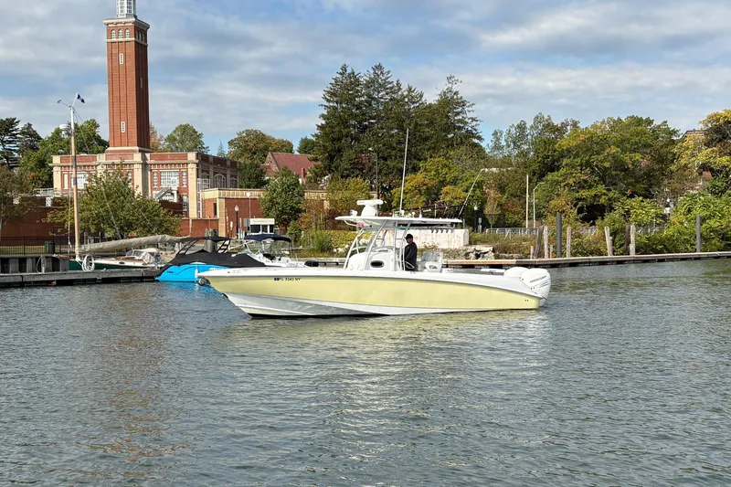 Slide: The Image of 2008 Boston Whaler 320 Outrage boat docked near a historic building and lush greenery. - 3