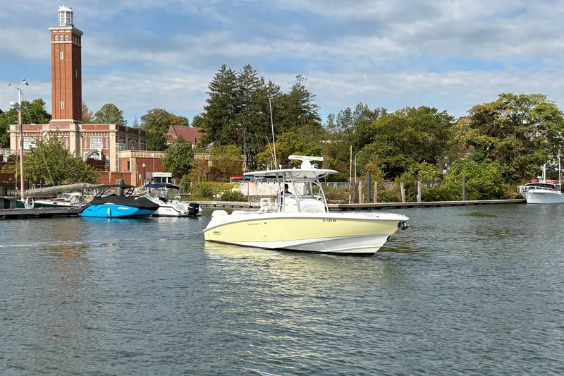 Slide: The Image of 2008 Boston Whaler 320 Outrage boat on calm water near a historic building. - 5