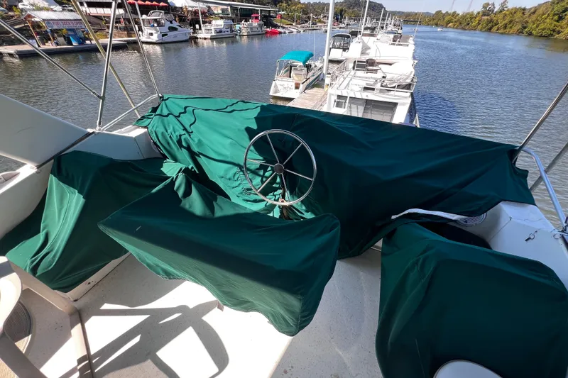 Slide: The Image of 1994 Gibson 44 Classic boat with green covers docked by a scenic river. - 12