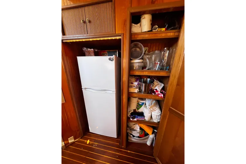 Slide: The Image of Wooden kitchen storage with white fridge and shelves filled with kitchenware, 1994 Gibson 44 Classic. - 22