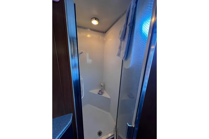 Slide: The Image of Compact shower area inside a 1994 Gibson 44 Classic boat, featuring a towel and toiletries. - 27