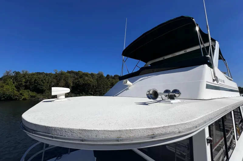 Slide: The Image of 1994 Gibson 44 Classic boat on water, clear sky, lush green shoreline. - 4