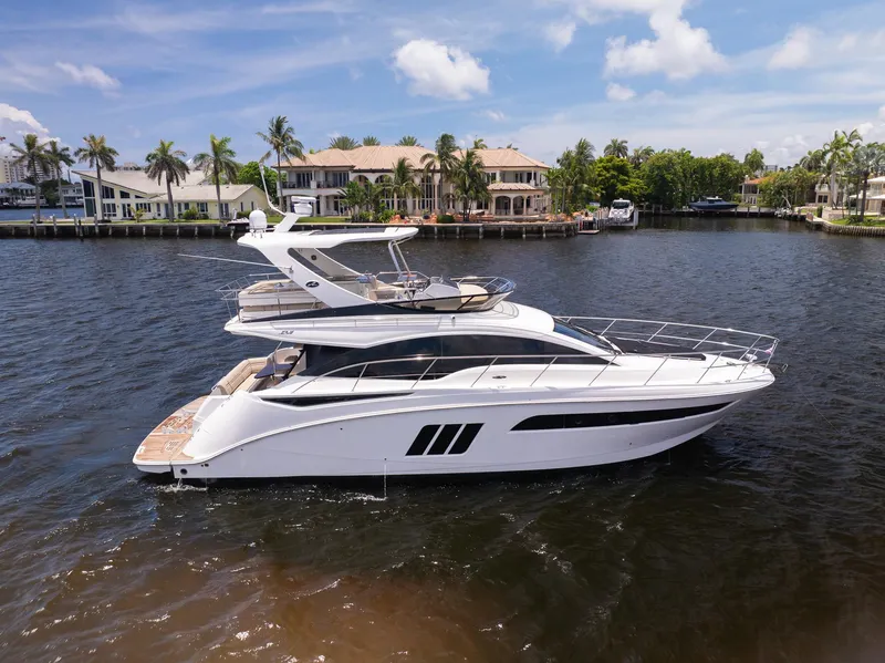The Image of 2016 Sea Ray 510 Fly yacht cruising on a sunny day near waterfront homes. - 0