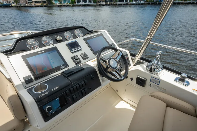 Slide: The Image of 2016 Sea Ray 510 Flybridge helm station with dual displays and waterfront view. - 32