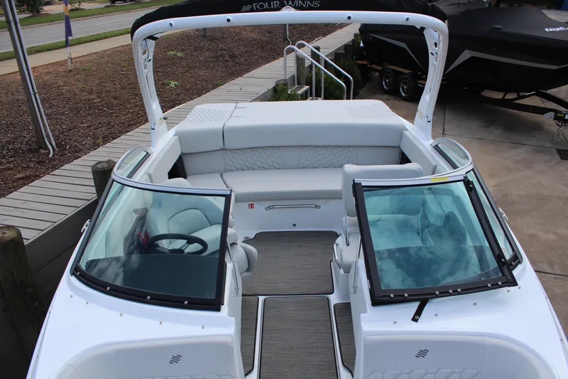 Slide: The Image of 2026 Four Winns H2 Freedom boat interior with seating and steering wheel, docked outdoors. - 18