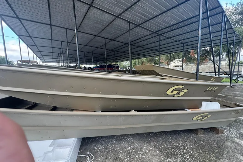 Slide: The Image of 2026 G3 Gator Tough 1436 boats under a metal canopy, stacked and ready for use. - 5