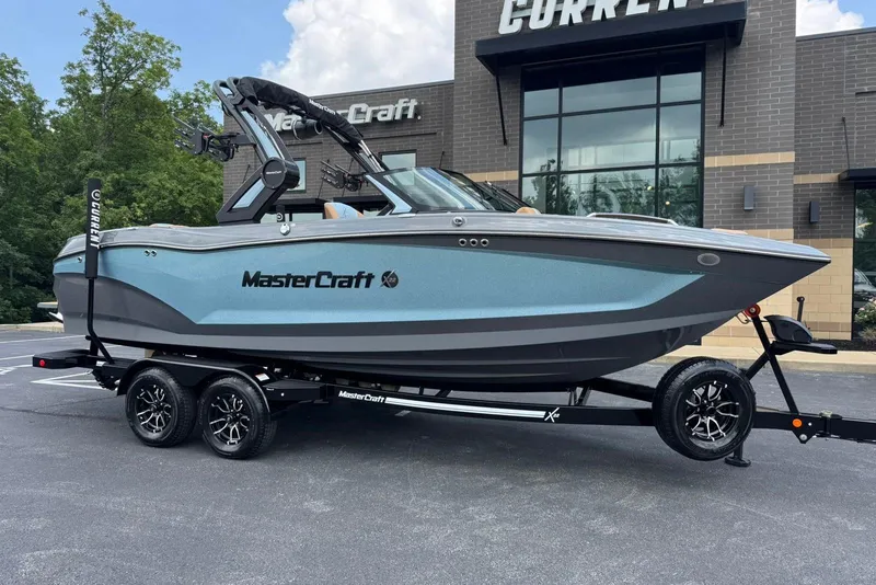 The Image of 2025 MasterCraft X22 boat on trailer outside dealership, showcasing sleek design and modern features. - 1