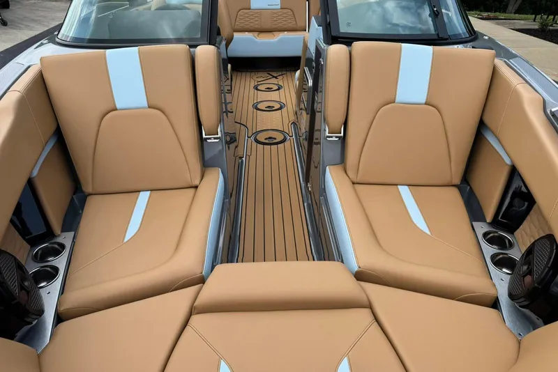 Slide: The Image of 2025 MasterCraft X22 boat interior with tan and blue seating, featuring cup holders and speakers. - 11