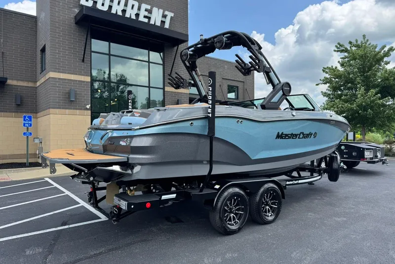 Slide: The Image of 2025 MasterCraft X22 boat on trailer outside a building, under a cloudy sky. - 3
