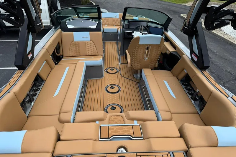 Slide: The Image of 2025 MasterCraft X22 boat interior with tan and blue seating, sleek design, and modern dashboard. - 7