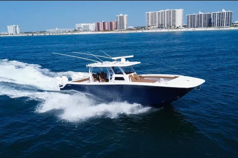 The Image of 2024 Invincible 46 Catamaran cruising on clear blue ocean near coastal city skyline. - 0