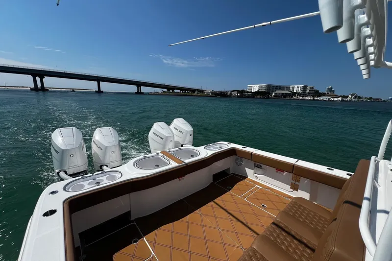 Slide: The Image of 2024 Invincible 46 Catamaran with Mercury engines cruising near a bridge on a sunny day. - 24