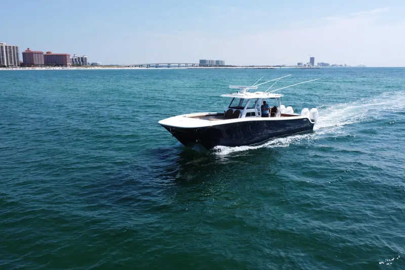 Slide: The Image of 2024 Invincible 46 Catamaran cruising on open water near coastal cityscape. - 31