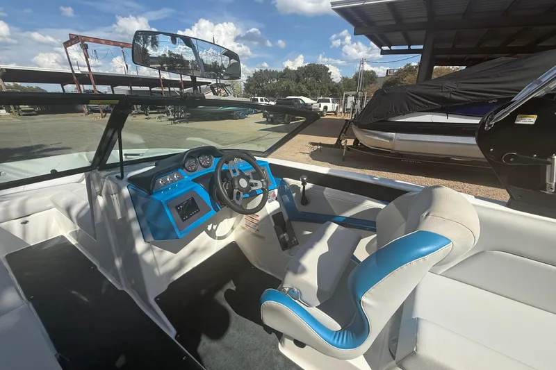 Slide: The Image of 2021 MasterCraft NXT24 boat interior with blue and white seating, steering wheel, and dashboard. - 10