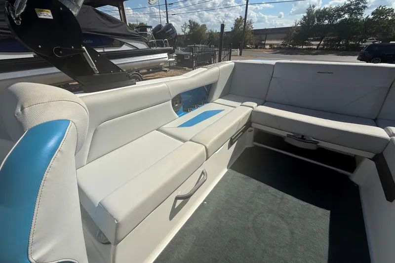 Slide: The Image of 2021 MasterCraft NXT24 boat interior with gray and blue seating, outdoor setting. - 15