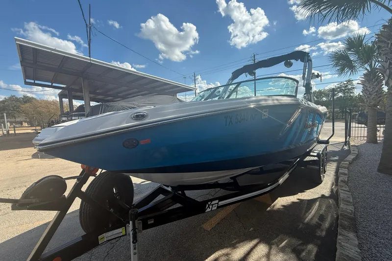 Slide: The Image of 2021 MasterCraft NXT24 boat on trailer under clear blue sky. - 4