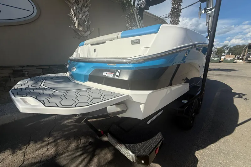 Slide: The Image of 2021 MasterCraft NXT24 boat with blue and white exterior, parked on a trailer. - 5
