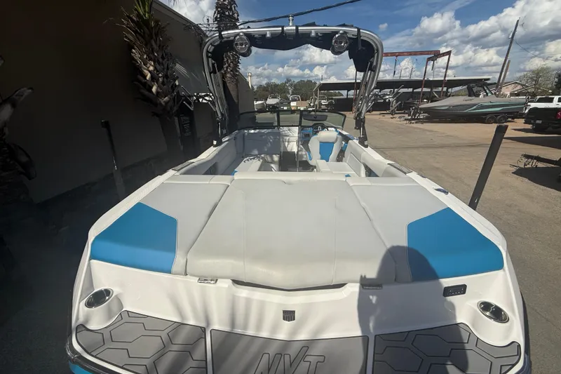 Slide: The Image of 2021 MasterCraft NXT24 boat with blue and white interior, parked outdoors under a sunny sky. - 8