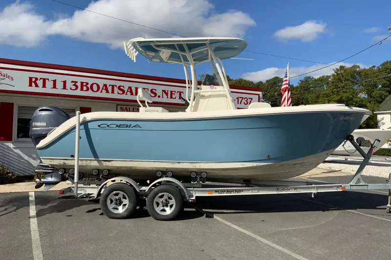 Slide: The Image of 2021 Cobia 220 Center Console boat on trailer at dealership, blue hull, Yamaha engine. - 1