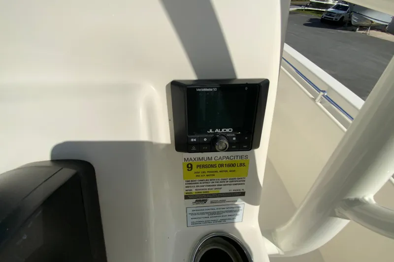 Slide: The Image of 2021 Cobia 220 Center Console boat dashboard with JL Audio system and capacity label. - 16