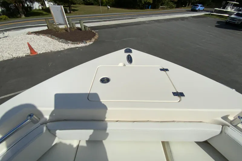 Slide: The Image of 2021 Cobia 220 Center Console boat bow with storage compartment, parked on asphalt. - 28