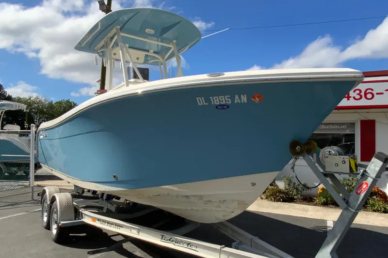 Slide: The Image of 2021 Cobia 220 Center Console boat on trailer, blue hull, sunny day background. - 3