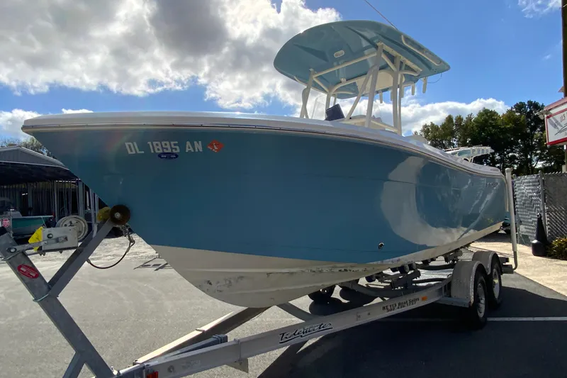 Slide: The Image of 2021 Cobia 220 Center Console boat on trailer, blue hull, parked outdoors. - 5