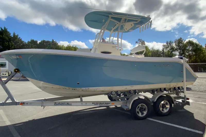 Slide: The Image of 2021 Cobia 220 Center Console boat on trailer, parked outdoors under cloudy sky. - 6