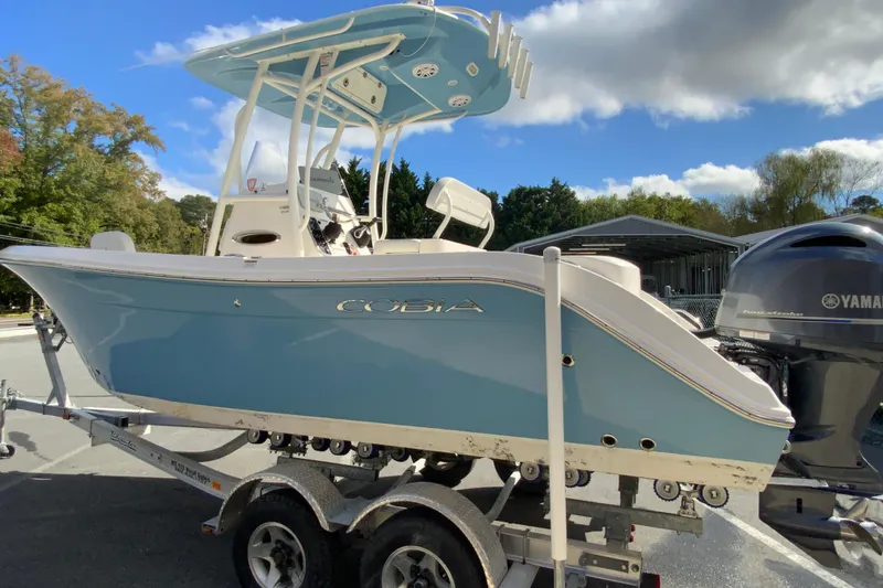 Slide: The Image of 2021 Cobia 220 Center Console boat on trailer, featuring Yamaha engine, under blue sky. - 7