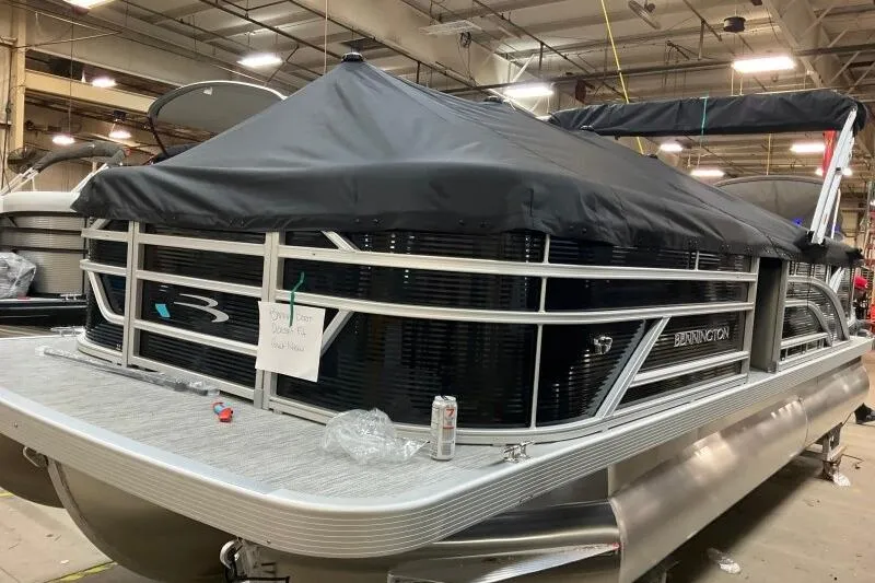 Slide: The Image of 2026 Bennington 22 SSRSF pontoon boat in a warehouse, covered and ready for display. - 11