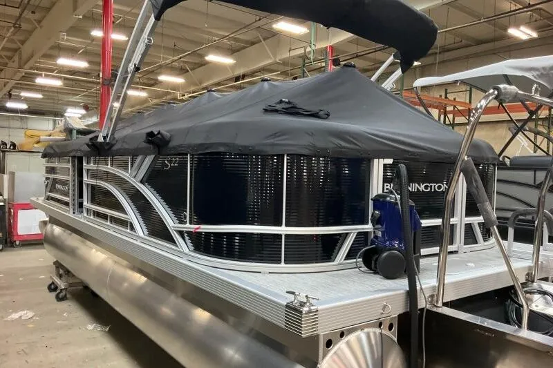 Slide: The Image of 2026 Bennington 22 SSRSF pontoon boat with black cover in a warehouse setting. - 12