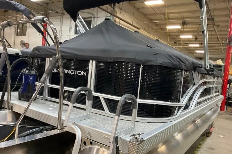 Slide: The Image of 2026 Bennington 22 SSRSF pontoon boat with black cover in a warehouse setting. - 13