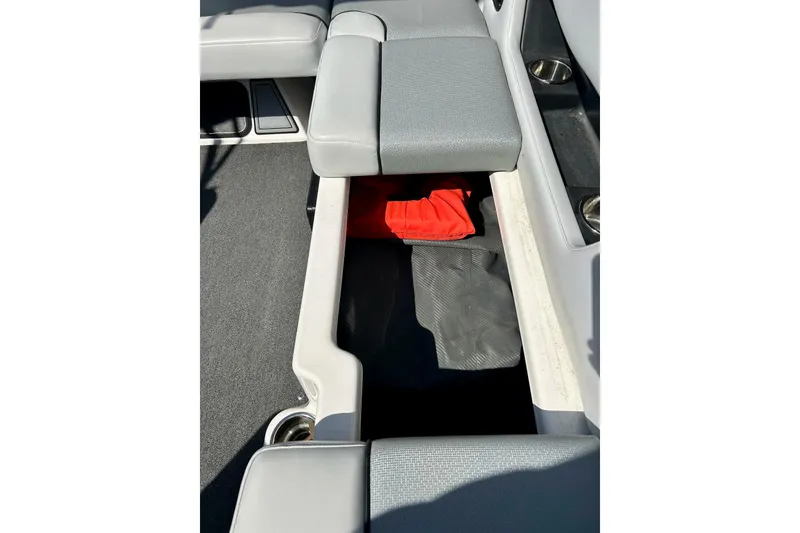 Slide: The Image of 2018 Moomba Helix boat interior storage compartment with gray seating and red life jacket. - 18