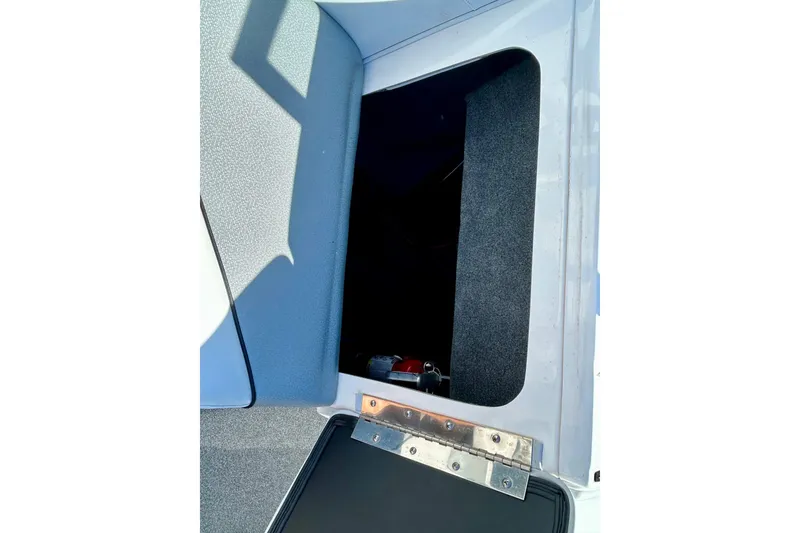 Slide: The Image of Open storage compartment in 2018 Moomba Helix boat, featuring gray interior and metal hinge. - 26