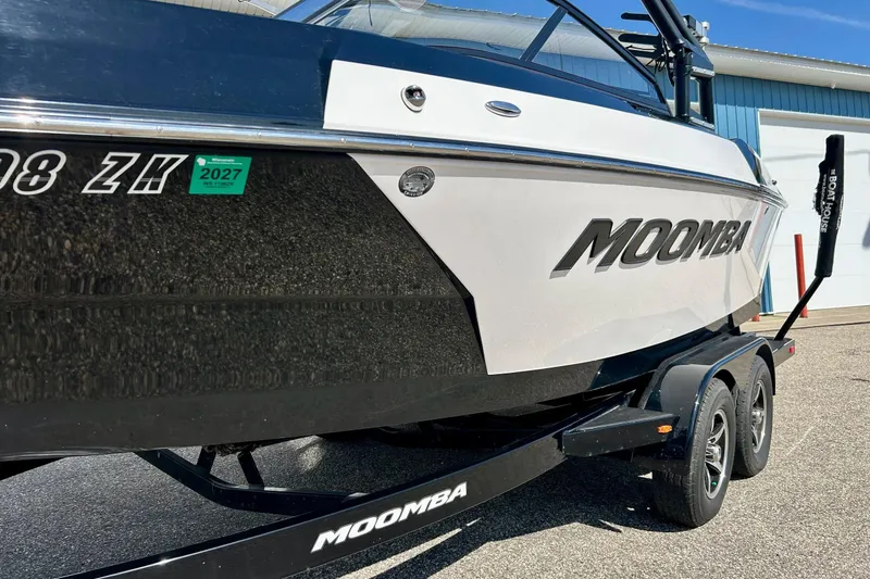 Slide: The Image of 2018 Moomba Helix boat on trailer, parked outdoors near a blue building. - 34