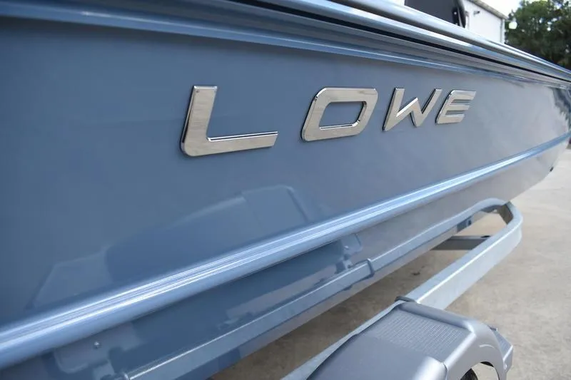 Slide: The Image of Close-up of 2026 Lowe Roughneck RX2070 CC boat's side detail, featuring sleek blue trim. - 16