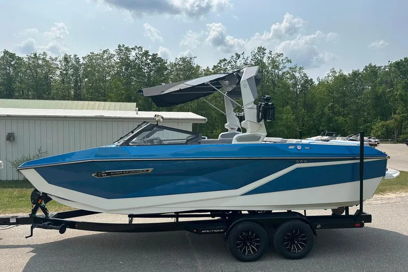 Slide: The Image of 2025 Nautique Super Air Nautique G23 boat in blue on trailer, parked outdoors. - 0