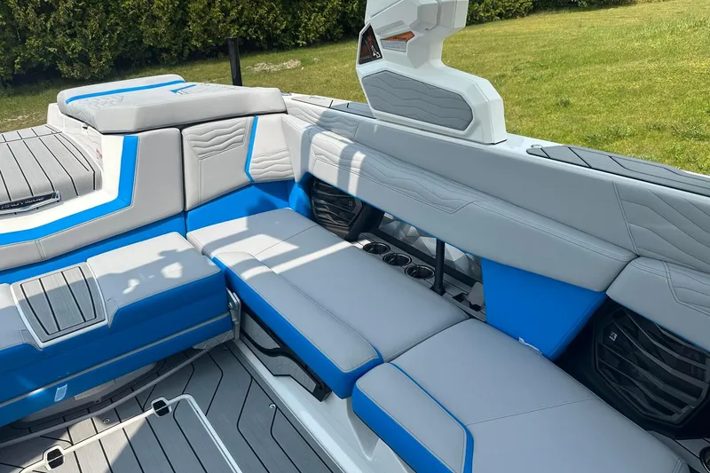 Slide: The Image of 2025 Nautique Super Air Nautique G23 interior with blue and gray seating, cup holders, and speakers. - 10