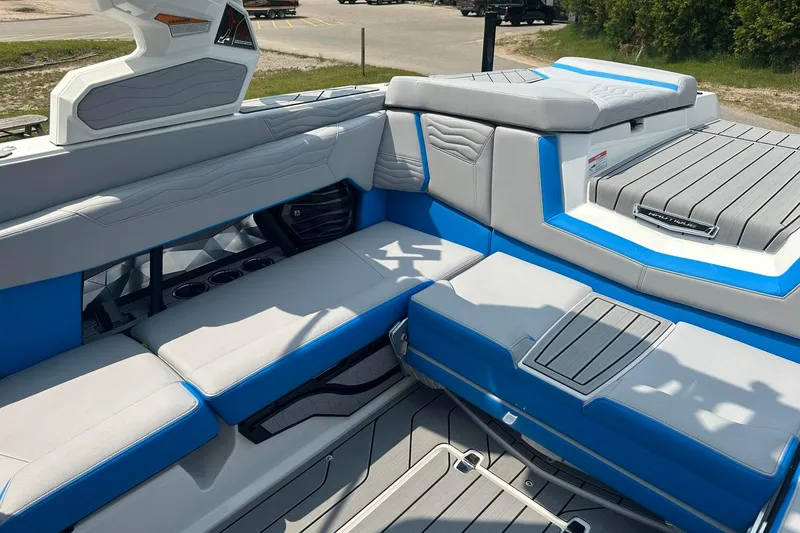 Slide: The Image of 2025 Nautique Super Air Nautique G23 interior with blue and gray seating, docked outdoors. - 11