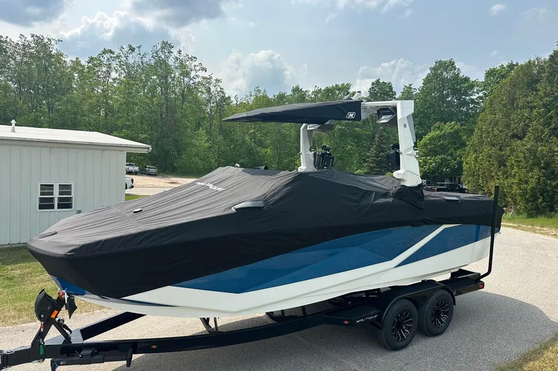 Slide: The Image of 2025 Nautique Super Air Nautique G23 boat covered on trailer, parked outdoors. - 25