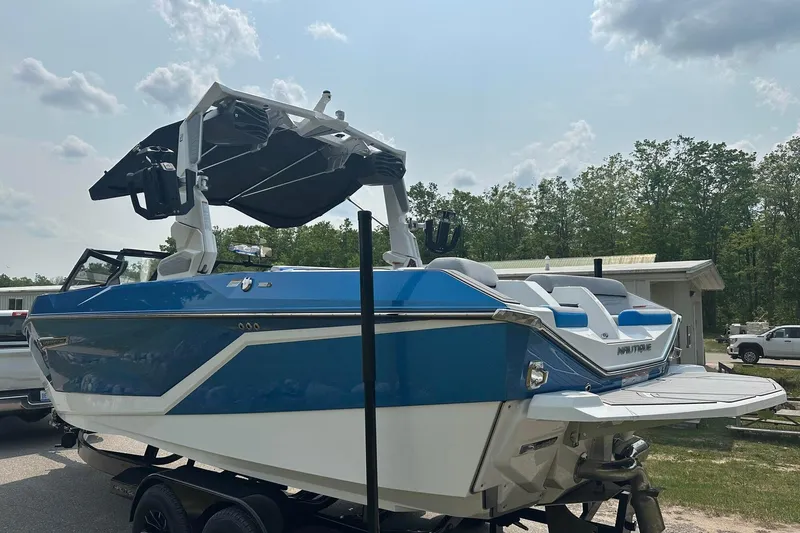 Slide: The Image of 2025 Nautique Super Air Nautique G23 boat, blue and white, on trailer, outdoors. - 3