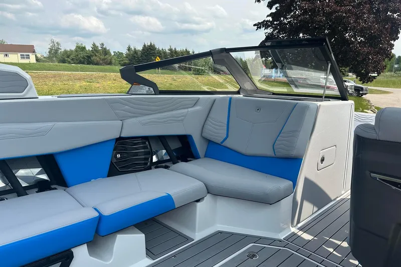 Slide: The Image of 2025 Nautique Super Air Nautique G23 interior with blue and gray seating, open-air view. - 9
