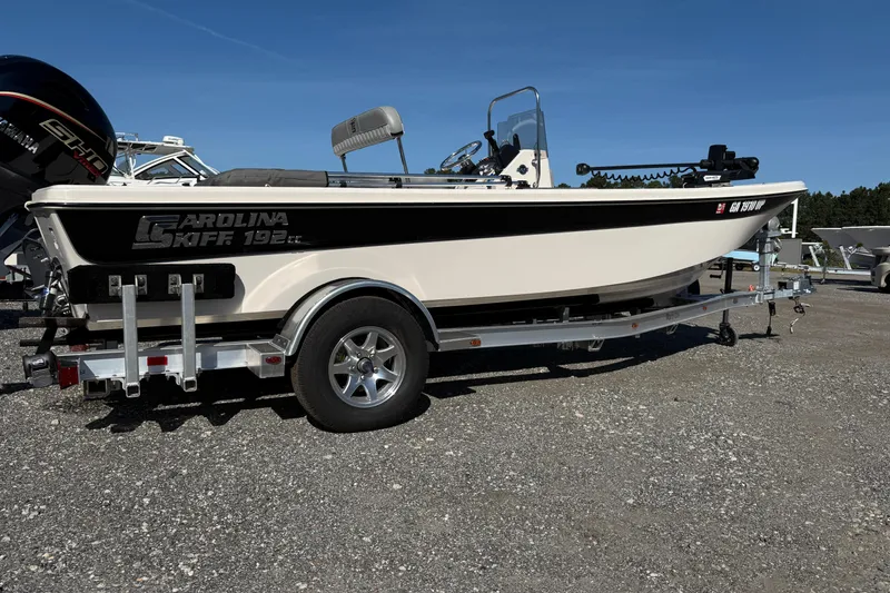 Slide: The Image of 2025 Carolina Skiff 192 JLS boat on trailer, parked outdoors under clear blue sky. - 20