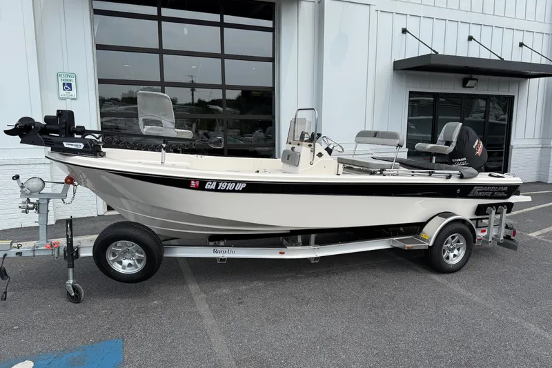 Slide: The Image of 2025 Carolina Skiff 192 JLS boat on trailer, parked outside a building. - 8