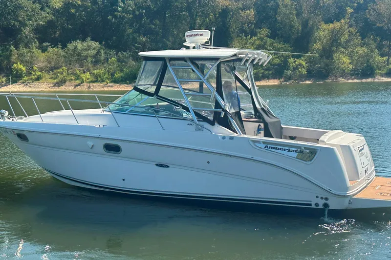 Slide: The Image of 2008 Sea Ray 290 Amberjack boat on calm water, surrounded by lush greenery. - 12