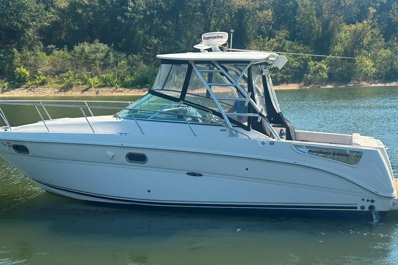 Slide: The Image of 2008 Sea Ray 290 Amberjack boat on calm water, surrounded by lush greenery. - 13