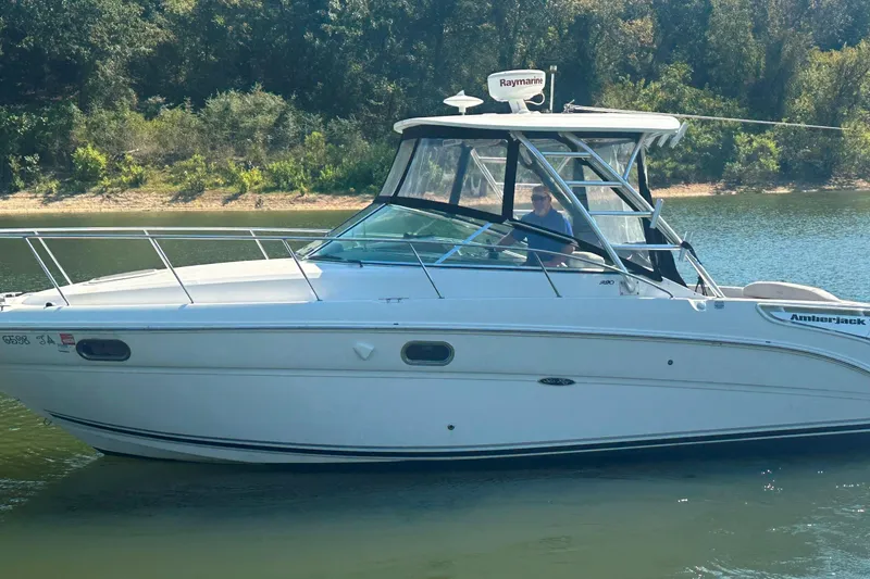 Slide: The Image of 2008 Sea Ray 290 Amberjack boat cruising on a calm lake with forested shoreline. - 15